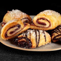 Rugelach decorated with powdered sugar and chocolate syrup.